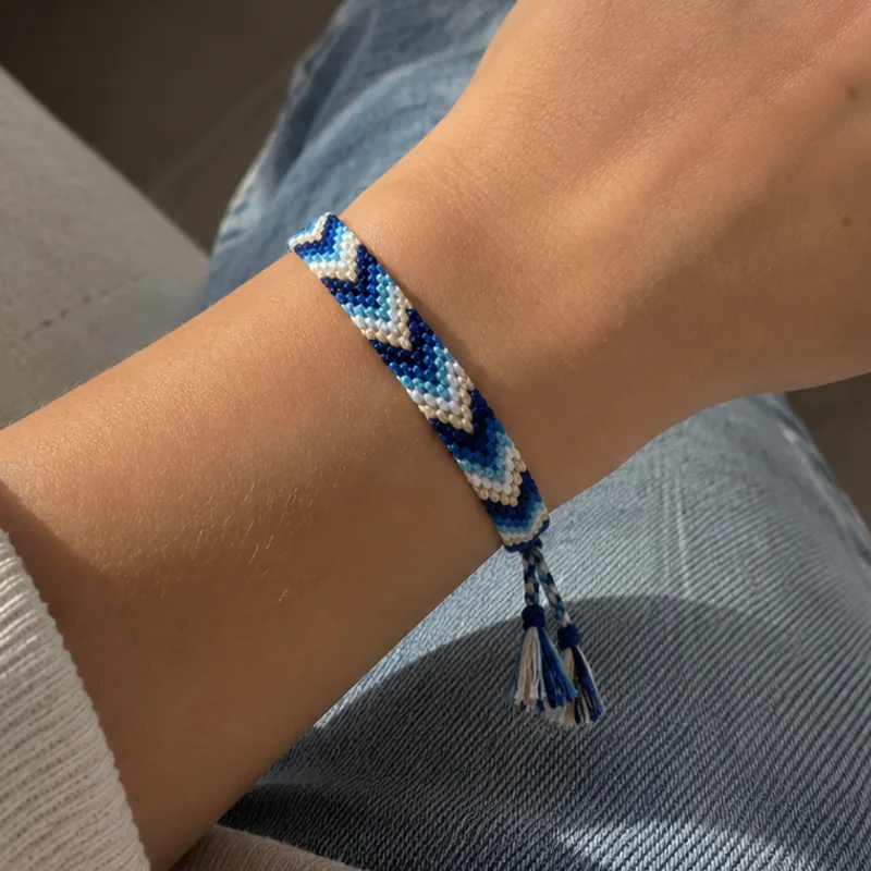Bracelet brésilien multicolore tissé en chevrons bleu marine, bleu, bleu ciel et blanc, porté au poignet