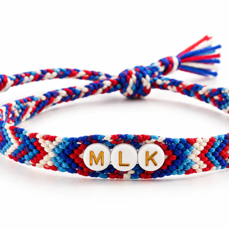 Bracelet brésilien en chevrons bleu, rouge et blanc avec trois perles blanches portant les lettres MLK
