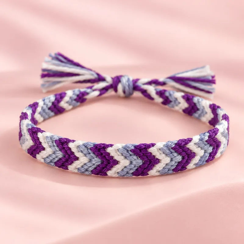 Bracelet brésilien simple tissé en chevrons violet, bleu lavande et blanc, sur fond rose